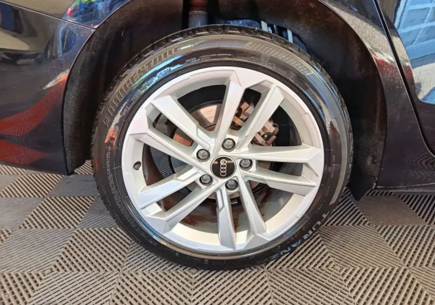 Gros plan sur la roue avant droite d'une Audi A3 noire 2022, mettant en valeur la jante en alliage argentée et le pneu Bridgestone.
