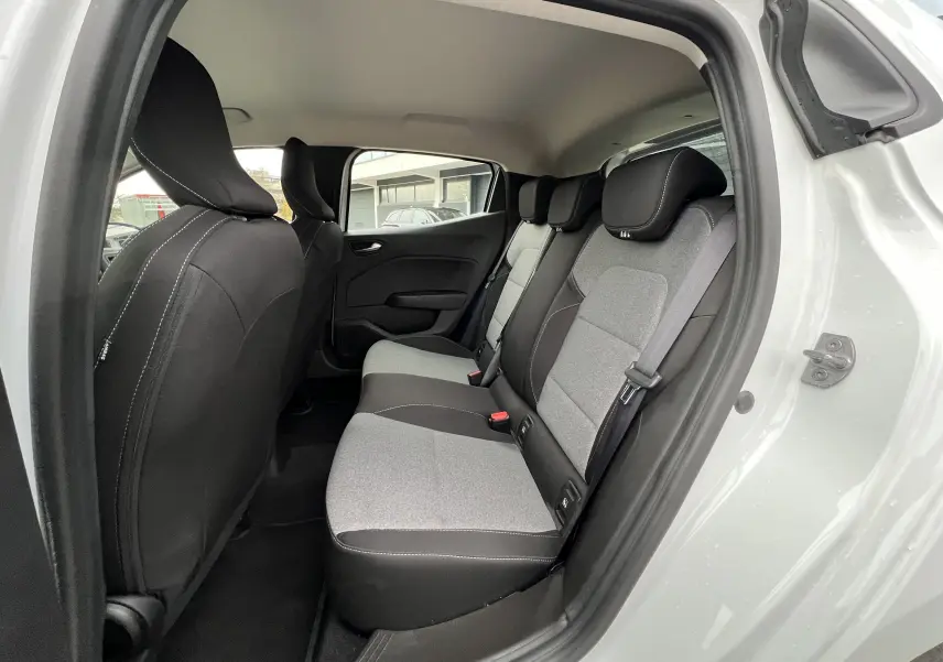 Vue intérieure arrière droite de la Renault Clio V blanche, sièges tissu gris avec appuie-têtes noirs contrastés.