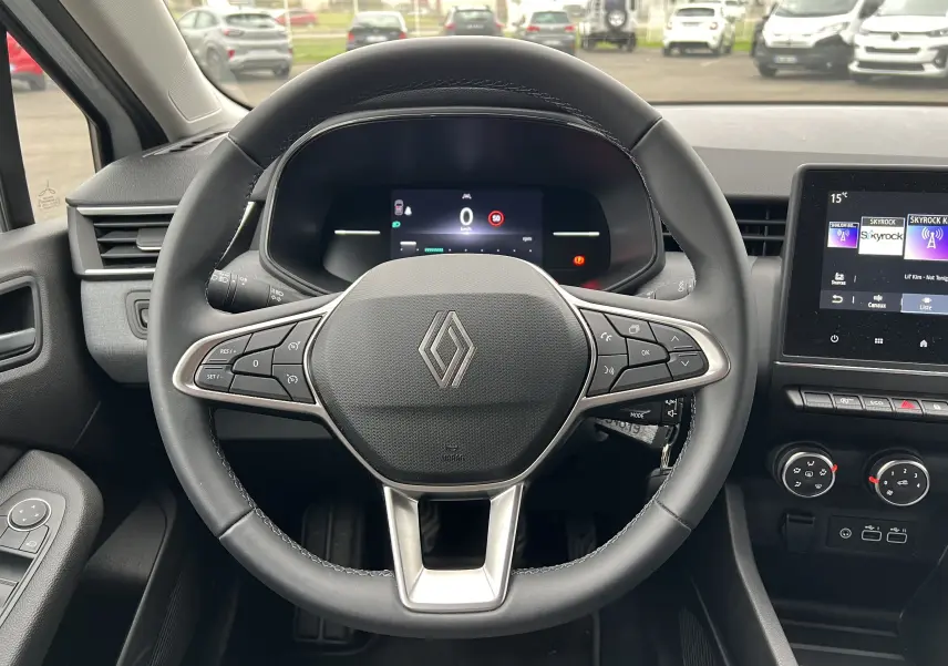 Vue intérieure centrée sur le volant cuir de la Renault Clio V 1.0 Tce 90 Evolution avec tableau de bord numérique et écran tactile.
