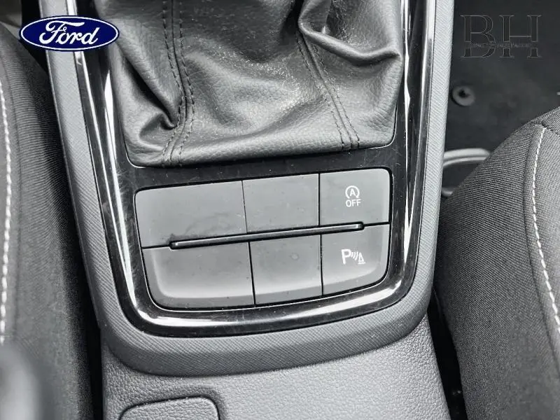 Gros plan sur la console centrale noire avec les boutons de contrôle du système start-stop et du radar de stationnement, intérieur tissu noir.