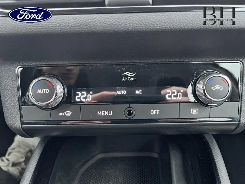 Panneau de commande de climatisation automatique affichant 22°C, avec boutons rotatifs et écran digital, intérieur noir.