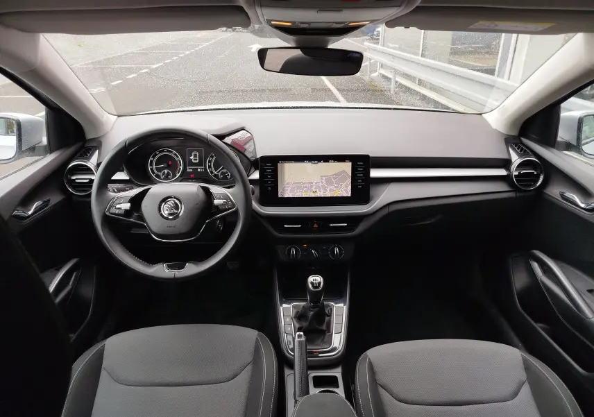 Vue intérieure frontale du poste de conduite de la Skoda Fabia gris argent, avec volant multifonction et écran tactile central.