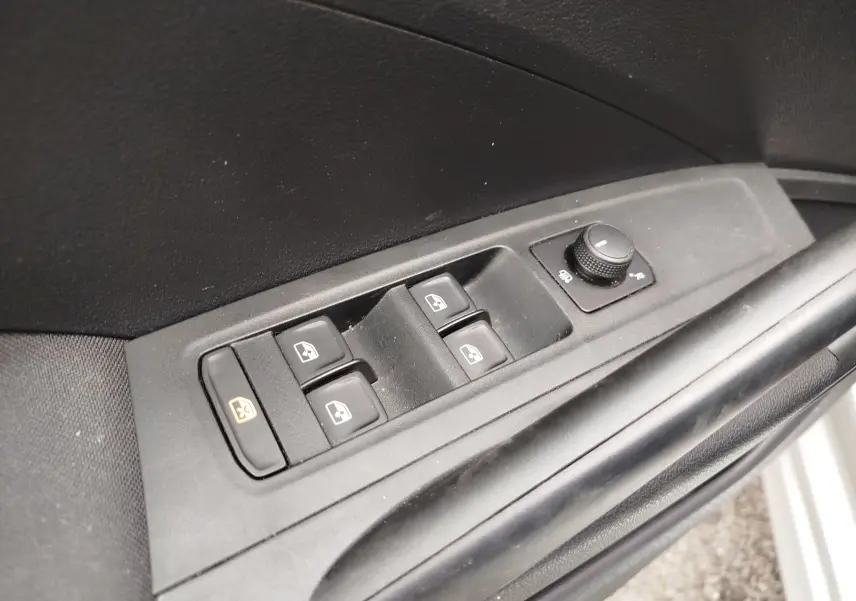 Gros plan sur les commandes de lève-vitres et réglage des rétroviseurs côté conducteur d'une Skoda Fabia gris argent 2023.