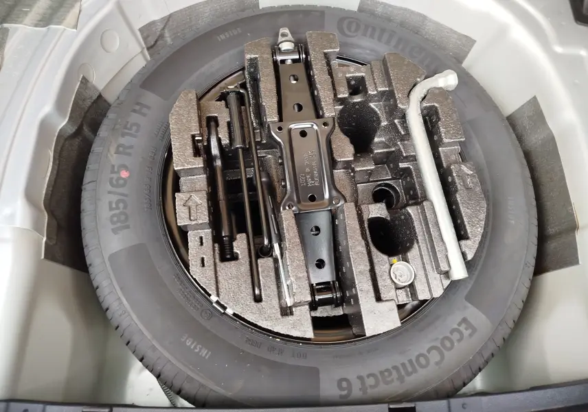 Vue plongeante sur la roue de secours et le kit de réparation logés dans le coffre d'une Skoda Fabia gris argent métallisé 2023.