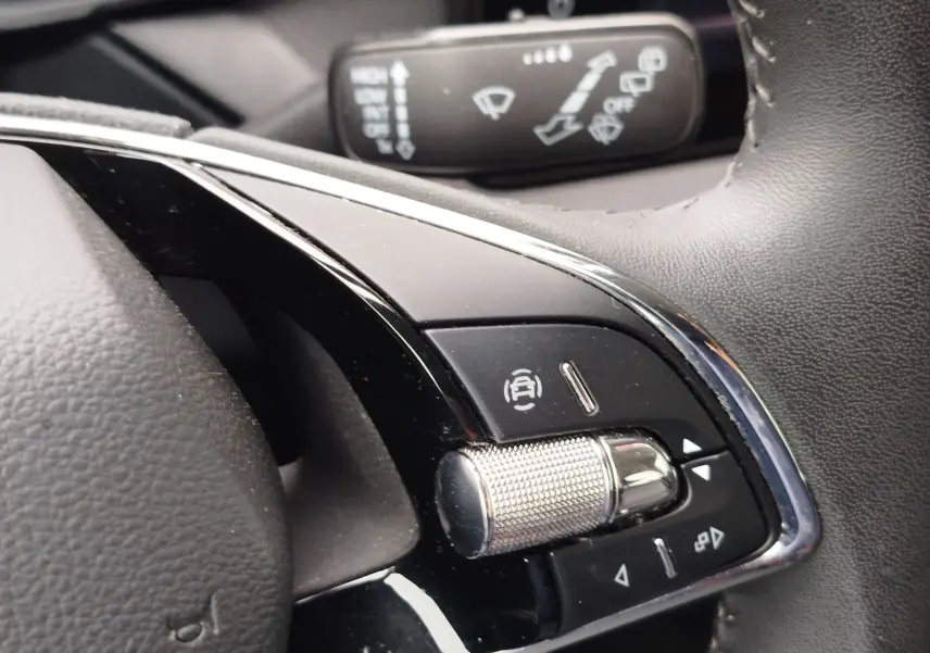 Gros plan sur les commandes du volant de la Skoda Fabia 2023, finition Ambition, avec molette métallique et boutons noirs.