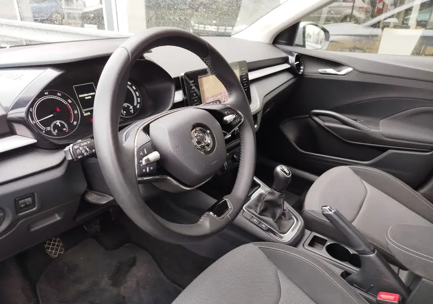 Vue intérieure côté conducteur de la Skoda Fabia 2023 avec volant multifonction, boîte manuelle et sellerie grise.