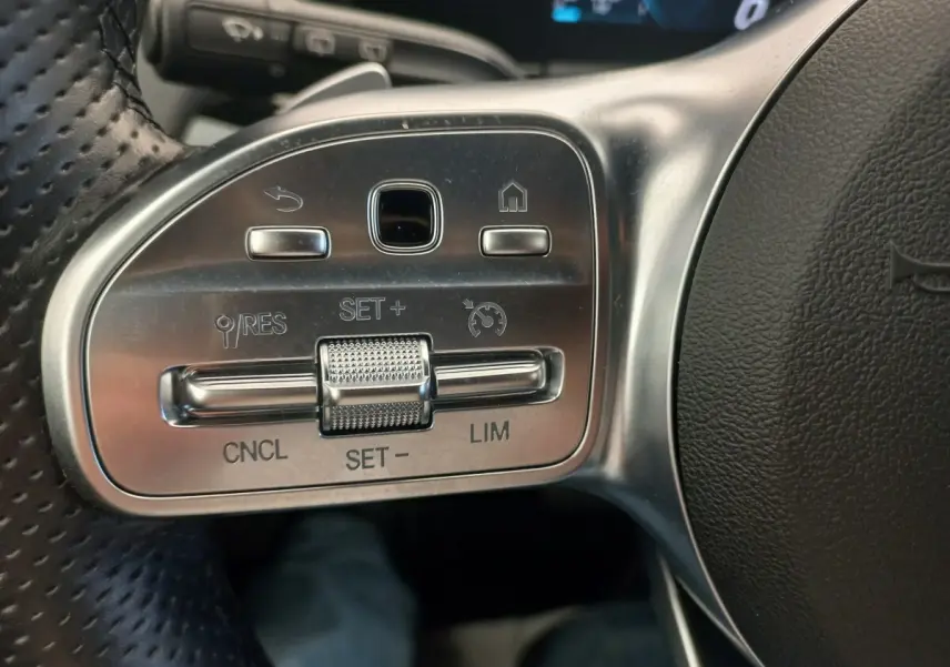Gros plan sur les commandes argentées du volant côté gauche de la Mercedes Classe A A 200 AMG Line noire.
