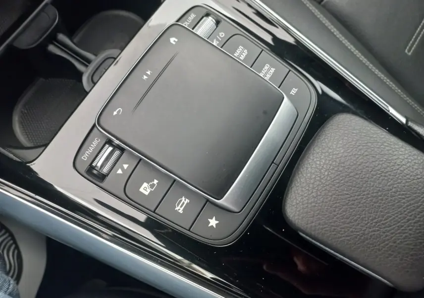 Vue rapprochée de la console centrale noire brillante avec pavé tactile et commandes du Mercedes Classe A Berline A 200 AMG Line.