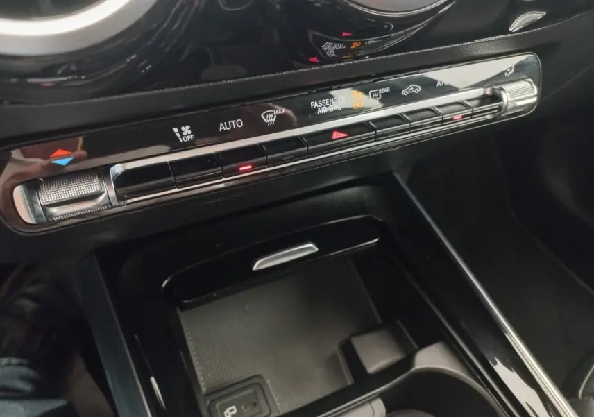 Gros plan sur la console centrale noire de la Mercedes Classe A A 200 AMG Line, avec commandes climatisation et rangement.