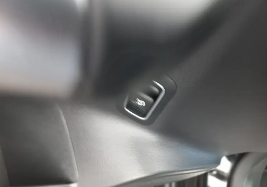 Détail du bouton de libération du coffre sur la garniture intérieure noire d’une Mercedes Classe A Berline A 200 AMG Line.