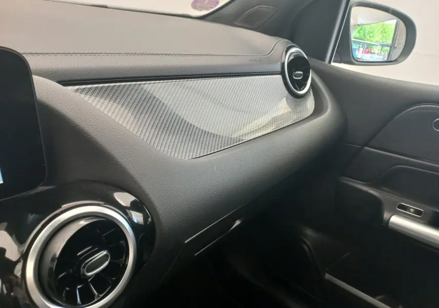 Vue intérieure côté passager de la planche de bord noire avec insert décoratif gris et aérateurs ronds chromés d'une Mercedes Classe A AMG Line.
