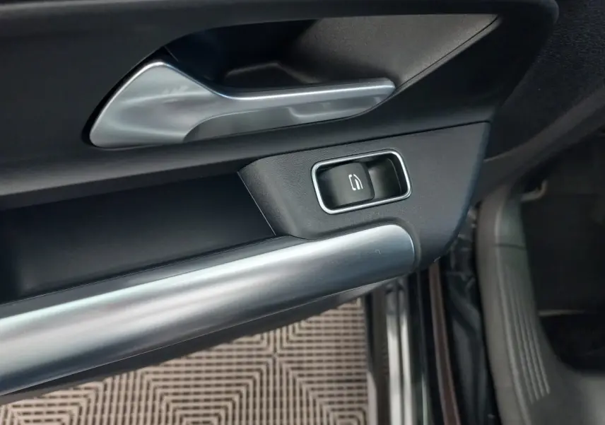 Gros plan sur la poignée intérieure et le bouton de verrouillage de la porte côté conducteur d’une Mercedes Classe A noire.