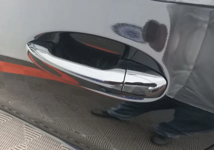 Poignée de porte chromée sur la porte côté droit d'une Mercedes Classe A Berline noire brillante.