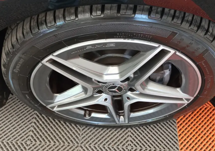 Gros plan sur la jante AMG argentée et le pneu noir d'une Mercedes Classe A berline A 200 AMG Line.