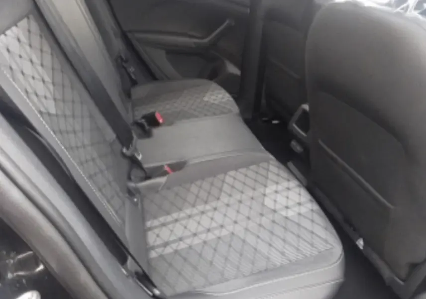 Vue intérieure du siège arrière côté gauche d’un Volkswagen T-Cross 2025 noir métal avec sellerie tissu à motifs losanges.
