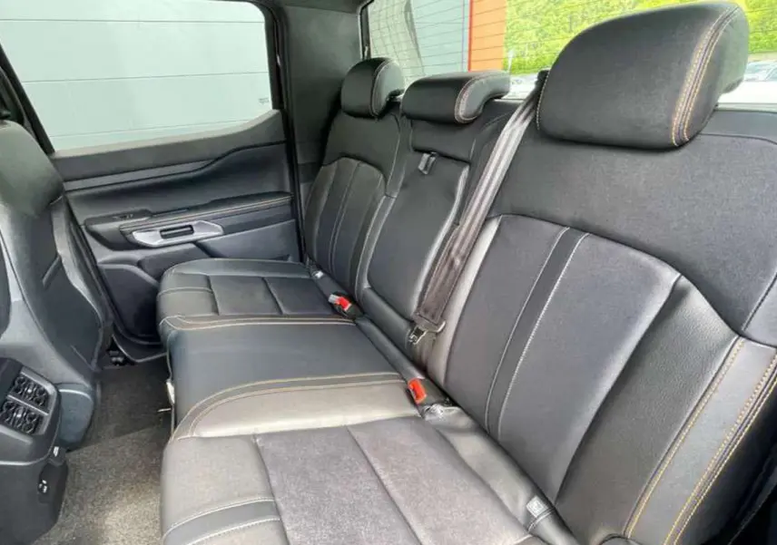 Vue intérieure arrière du Ford Ranger 2025 Wildtrak Plus, sièges en cuir noir agate avec surpiqûres contrastées.