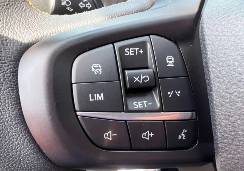 Gros plan sur les commandes au volant du Ford Ranger 3.0 V6 240 Wildtrak Plus noir agate, boutons de régulateur et volume.