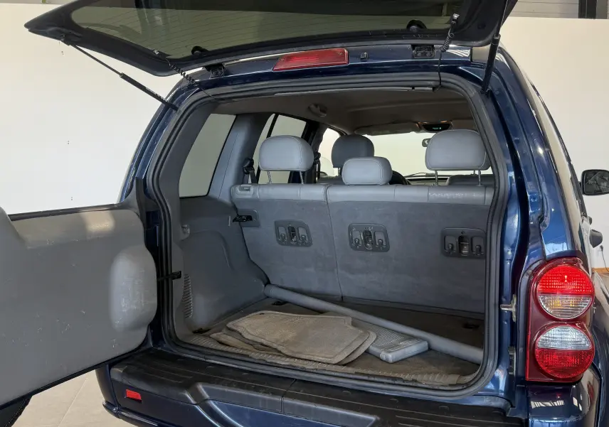 Vue arrière ouverte du Jeep Cherokee bleu 2005 montrant le coffre spacieux et les sièges arrière gris.