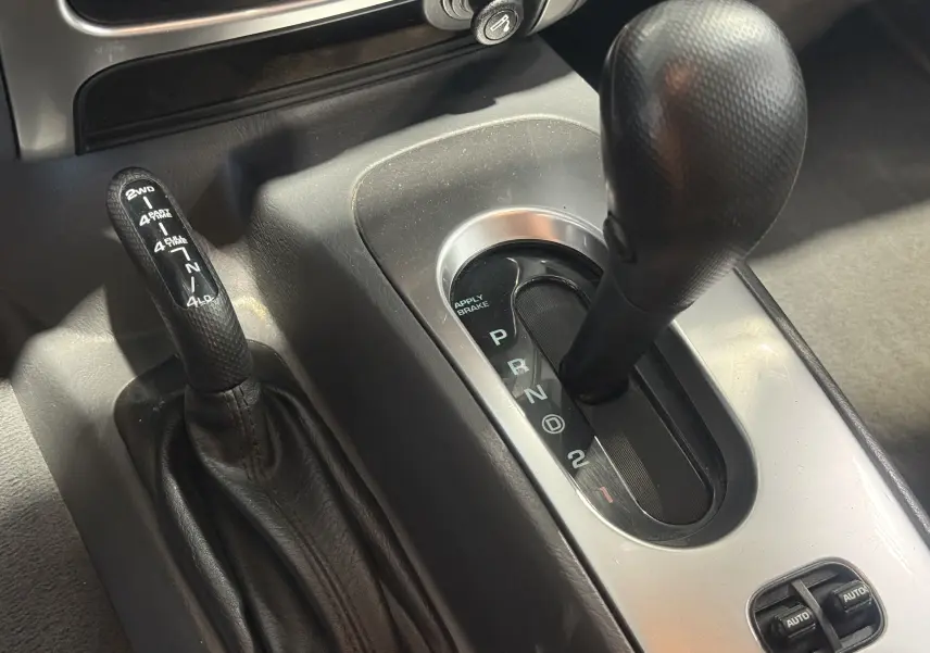 Le levier de vitesses automatique et la commande de transmission 4x4 du Jeep Cherokee bleu 2005 en gros plan intérieur.