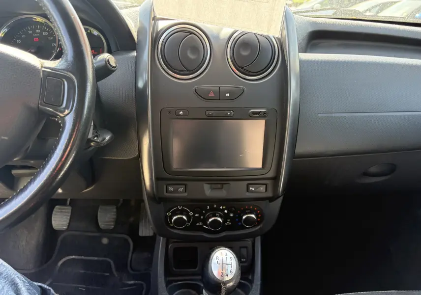 Vue intérieure du tableau de bord et console centrale du Dacia Duster 1.5 DCI 110 2014 avec levier de vitesses manuel.