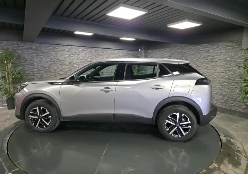 Vue de profil côté gauche d'un Peugeot 2008 gris métallisé avec jantes noires et toit noir contrasté.