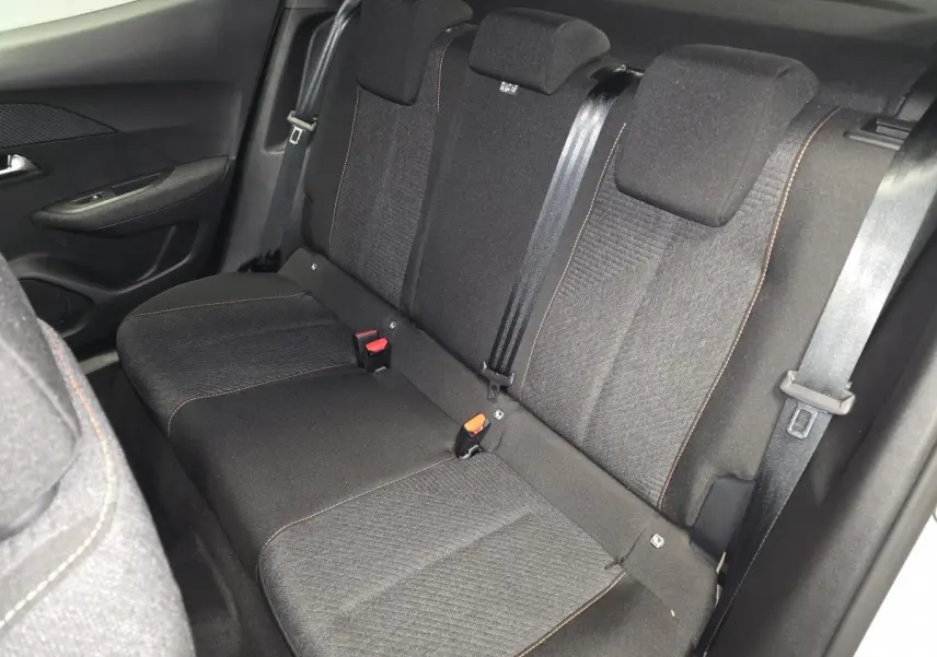 Vue intérieure de la banquette arrière en tissu gris foncé avec surpiqûres orange du Peugeot 2008 1.2i Hybrid 2025.