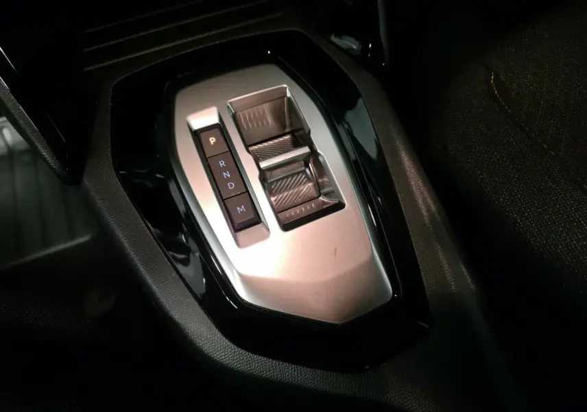 Gros plan sur la commande de boîte automatique argentée du Peugeot 2008 gris, avec levier et boutons P, R, N, D, M.