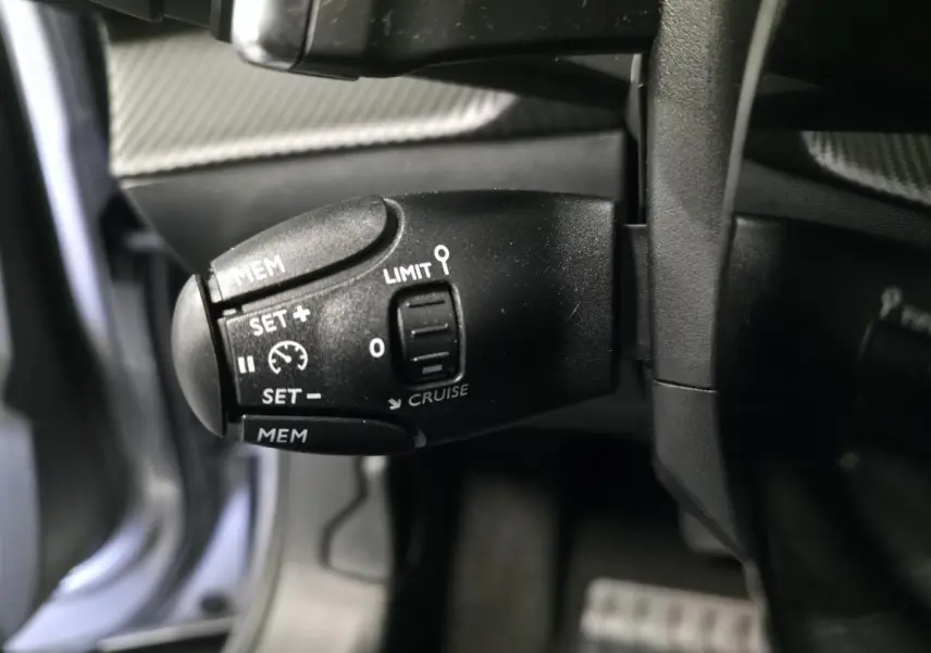 Gros plan sur la commande de régulateur de vitesse noire dans l’habitacle du Peugeot 2008 gris 2025.