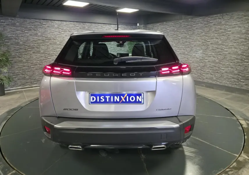 Vue arrière d'un Peugeot 2008 gris métallisé avec feux arrière LED allumés et double sortie d'échappement chromée.