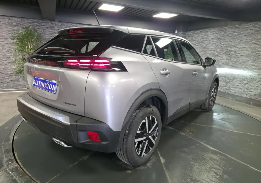 Vue 3/4 arrière droite d’un Peugeot 2008 gris métallisé avec feux arrière LED 3 griffes et jantes tôle 16 pouces.