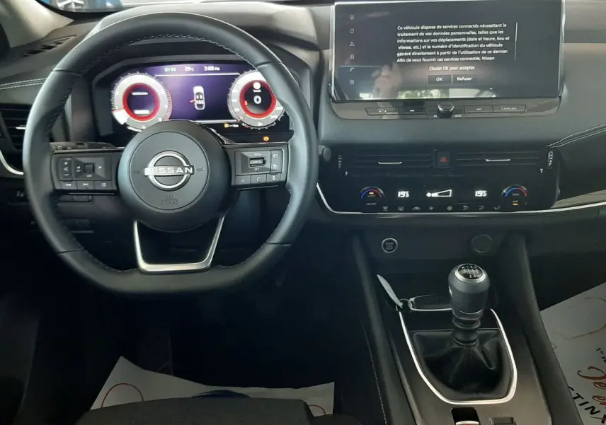 Vue intérieure du tableau de bord du Nissan Qashqai 2022 avec volant multifonction et écran tactile central allumé.