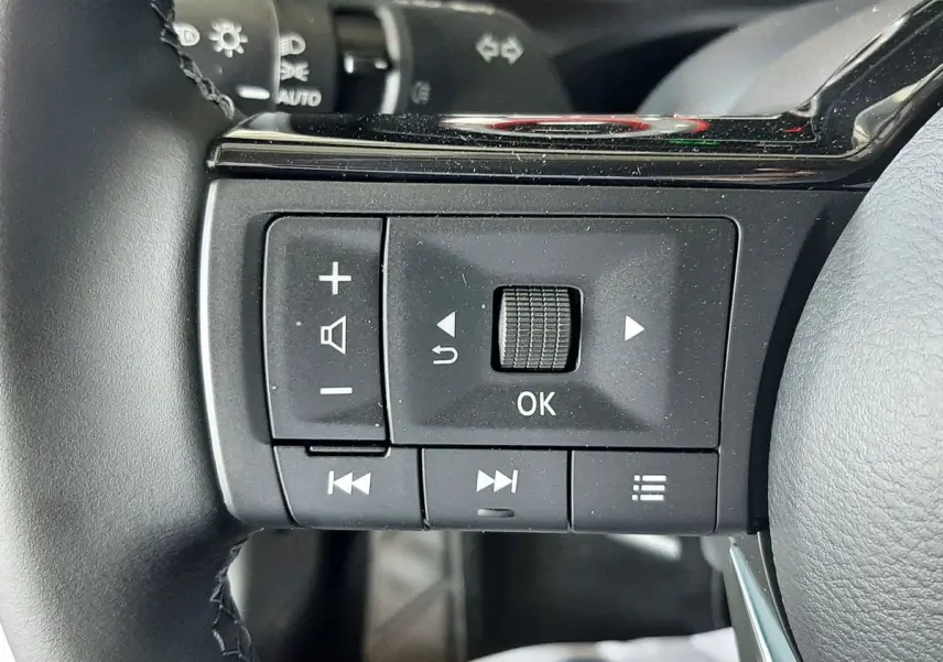 Gros plan sur les commandes multifonctions noires du volant du Nissan Qashqai blanc lunaire 2022.