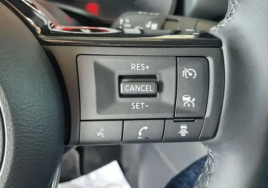 Gros plan sur les commandes de régulateur de vitesse au volant cuir noir du Nissan Qashqai blanc lunaire 2022.