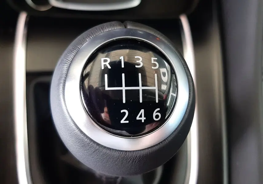 Gros plan sur le levier de vitesse manuelle noir et argenté du Nissan Qashqai blanc lunaire 2022.