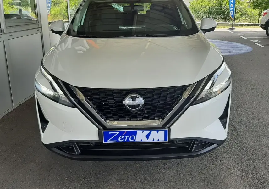 Vue frontale d'un Nissan Qashqai blanc lunaire 2022 avec calandre noire et plaque Zéro KM visible.