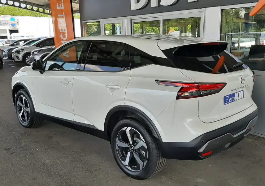Nissan Qashqai blanc lunaire vu en 3/4 arrière droit, avec jantes noires et toit noir contrastant.