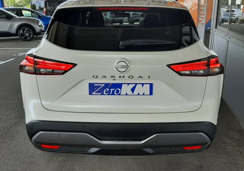 Vue arrière d'un Nissan Qashqai blanc lunaire 2022 avec feux LED et logo bien visibles sur un parking couvert.