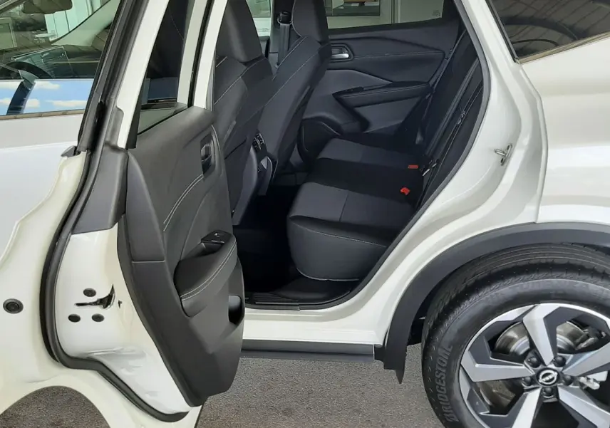 Vue côté gauche arrière du Nissan Qashqai blanc lunaire 2022, porte ouverte sur l'habitacle et sièges noirs.