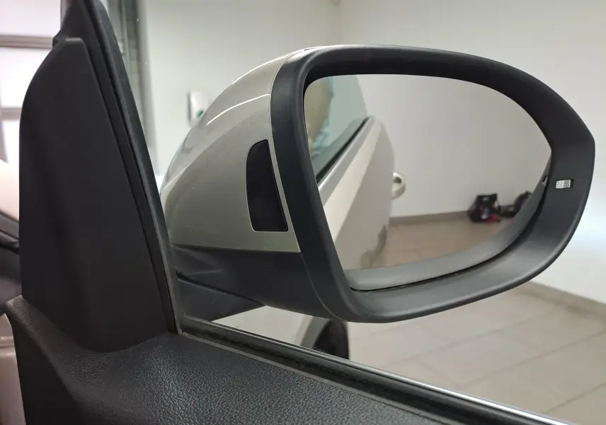 Rétroviseur extérieur côté gauche gris ivoire du Volkswagen T-Roc Cabriolet 2022 avec capote noire visible en reflet.