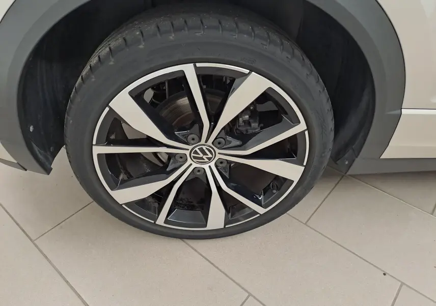 Gros plan sur la jante 19'' Misano bicolore noir et argent du côté gauche du Volkswagen T-Roc Cabriolet gris ivoire.