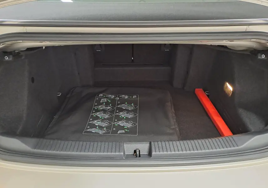 Coffre ouvert du Volkswagen T-Roc Cabriolet gris ivoire 2022, intérieur noir avec notice et triangle de sécurité rouge.