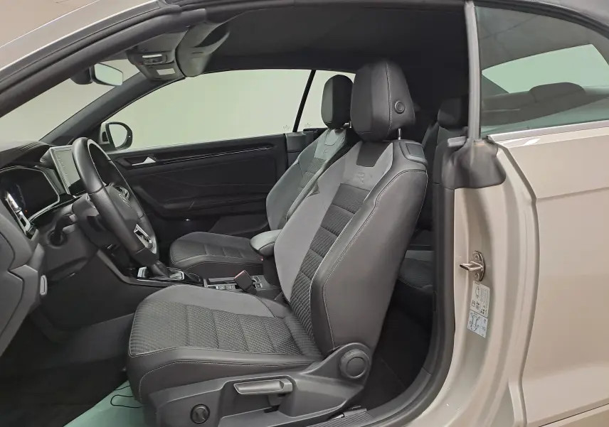 Intérieur du Volkswagen T-Roc Cabriolet gris ivoire, vue côté gauche avec sièges sport R-Line en tissu et cuir noir.
