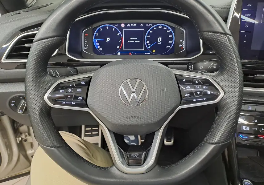 Vue rapprochée du volant cuir perforé et tableau de bord numérique du Volkswagen T-Roc Cabriolet 1.5 TSI R-Line 2022.
