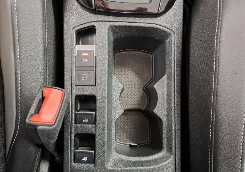 Gros plan sur la console centrale du Volkswagen T-Roc Cabriolet 2022, avec boutons et porte-gobelets noirs.