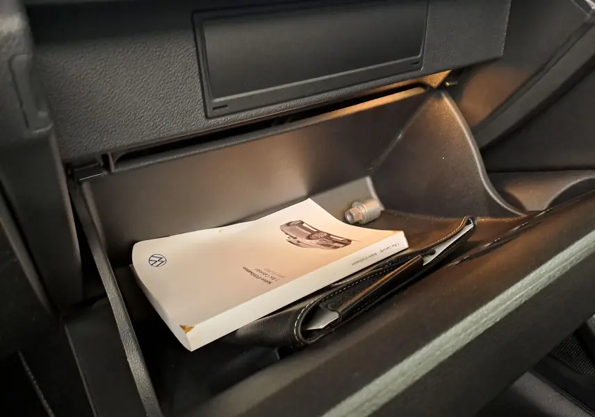 Boîte à gants ouverte du Volkswagen T-Roc Cabriolet 1.5 TSI 150 DSG7 R-Line avec manuel et pochette noire visibles