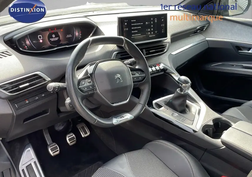 Intérieur moderne du Peugeot 3008 GT 2023, vue côté conducteur, volant compact et levier de vitesse manuel visibles.