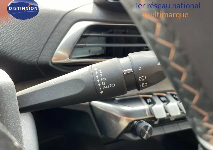 Gros plan sur la commande d'essuie-glace à gauche du volant en cuir noir avec surpiqûres orange du Peugeot 3008 gris platinium.