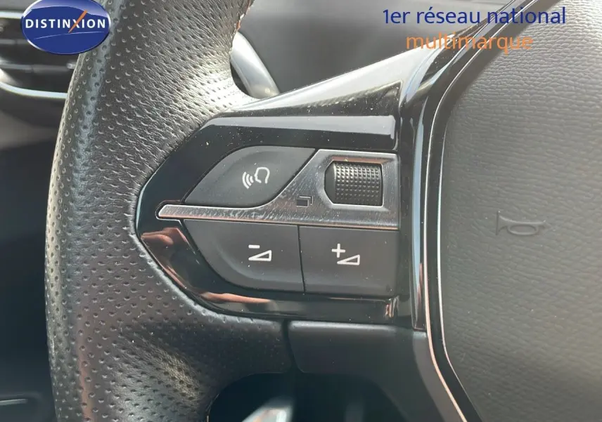 Gros plan sur les commandes au volant en cuir perforé noir du Peugeot 3008 gris platinium 2023.