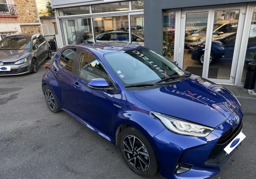 Toyota Yaris Hybride Design 116h bleu métal vue 3/4 avant droit avec jantes alliage et phares LED allumés.