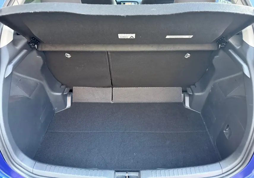Coffre ouvert vu de l'arrière d'une Toyota Yaris Hybride Design 116h bleu métal, espace de rangement vide et propre.